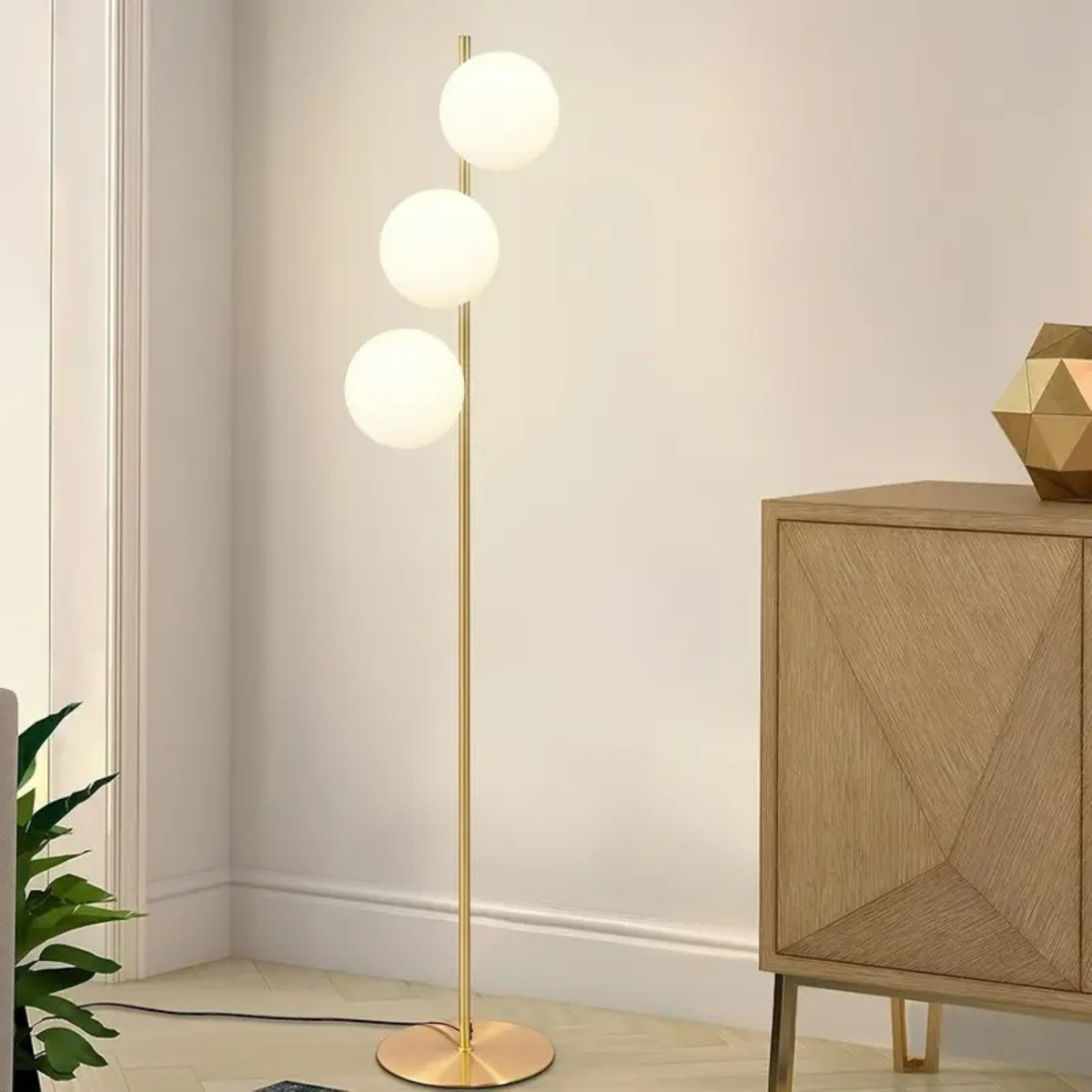 Gouden vloerlamp met drie bollen in woonkamer